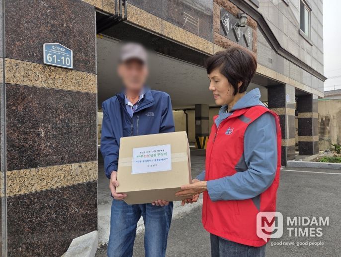 명예사회복지공무원이 대상자 가정을 방문해 꾸러미를 전달하는 모습